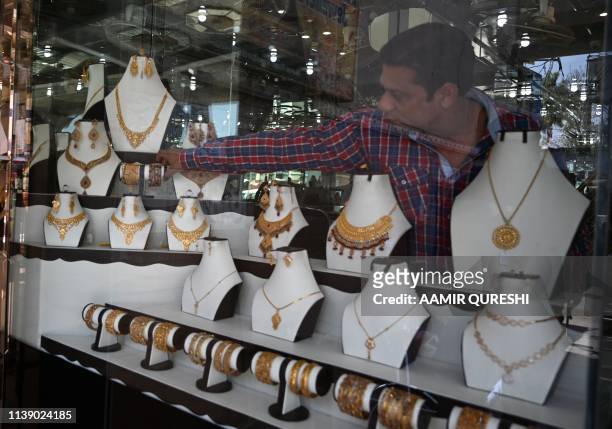 N this pictures taken on April 22 a Pakistani jeweller arranges jewellery in a window at his shop in Rawalpindi.