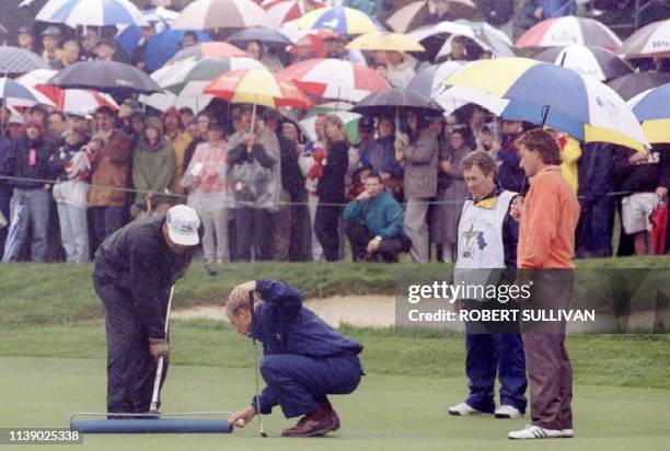 Ryder Cup European team members Per-Ulrik Johansson and Bernhard Langer wait on the green as water is squeeged off the green before they putt on the...