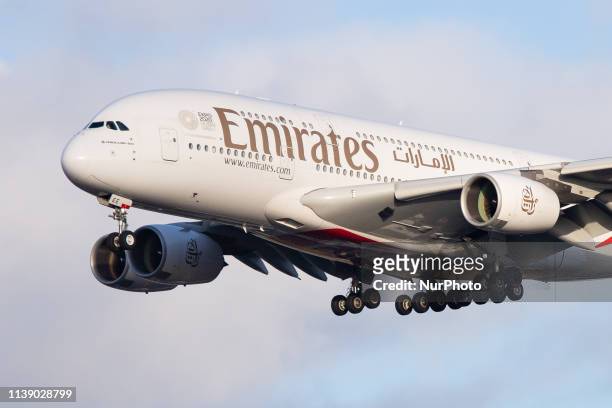 Emirates Airbus A380-800 airplane with registration A6-EEE landing at Amsterdam Schiphol AMS EHAM International Airport in a blue sky with clouds...