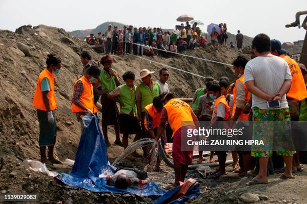 Graphic content / Search and rescue volunteers wash the dead body of miner recovered after a landslide in a jade mining area in Hpakant, in Myanmar's...
