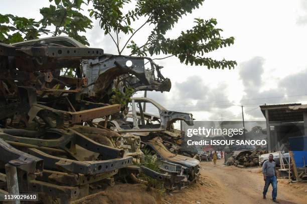 Residents walk past piles of destroyed vehicles in the Adjame neighborhood of Abidjan, on April 23, 2019. - The Ivorian authorities plan to clear the...
