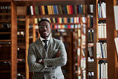 An African AmericanAn African American man in a business suit standing in a library in the reading room man in a business suit standing in a library in the reading room.