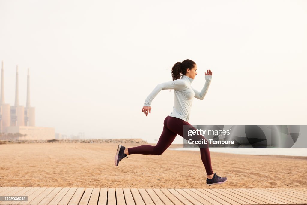One woman running and exercising in Barcelona near the beach.