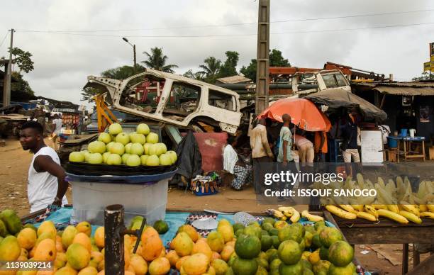 Residents hold a market amongst piles of destroyed vehicles in the Adjame neighborhood of Abidjan, on April 23, 2019. - The Ivorian authorities plan...