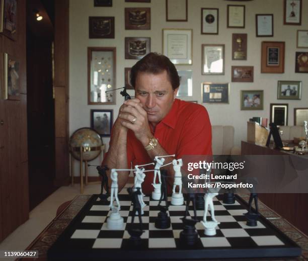 American golfer Raymond Floyd contemplating his next move at a chess set with golfers as chess pieces at his home, circa 1989.