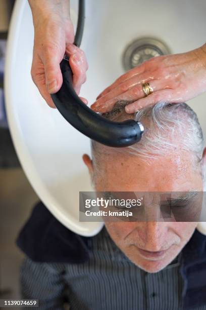 hairdresser washing senior man's hair - shower man woman washing stock pictures, royalty-free photos & images