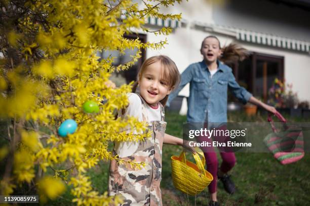 two children running in a back yard searching for easter eggs - easter egg hunt stock pictures, royalty-free photos & images