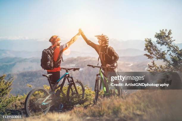 die fahrt war fantastisch, zwei mountainbiker auf einem berggipfel - bike headset stock-fotos und bilder