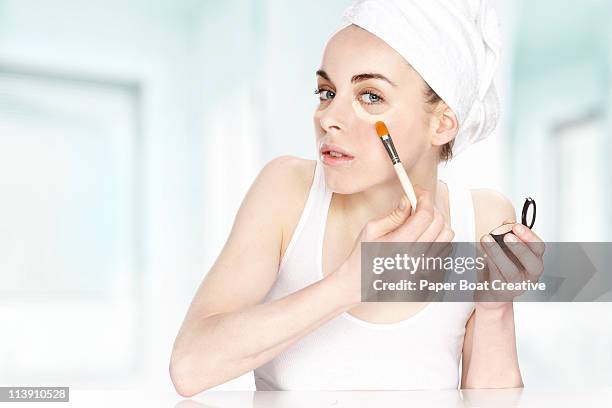 young woman putting aconcealer under her eyes - beautiful woman and tired stock pictures, royalty-free photos & images