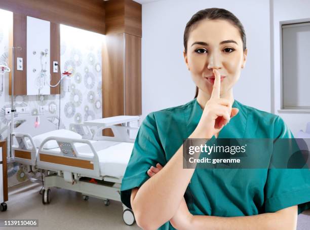 young female nurse making a silence hand gesture in hospital - quiet gesture stock pictures, royalty-free photos & images