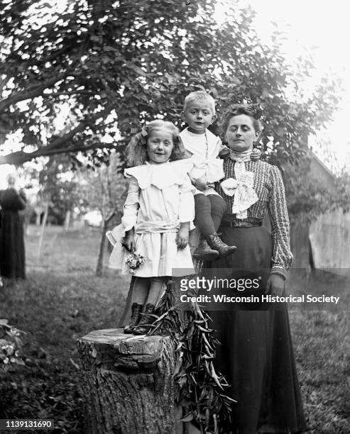 Outdoor family portrait of Jennie, Edgar, and Florentina Krueger posing with a log that has been carved into a chair, Emmet, Wisconsin, August 10,...