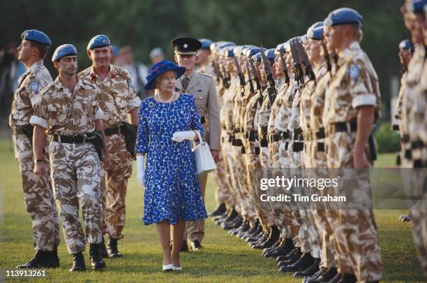 Queen Elizabeth II, wearing a blue and white dress with a blue hat, as she inspects UN peacekeeping troops during a visit to Cyprus, 21 October 1993....