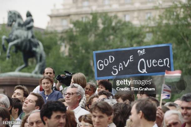 Banner declaring 'God save the Queen' is held aloft by a crowd gathered to welcome Queen Elizabeth II to Budapest during a three-day state visit to...