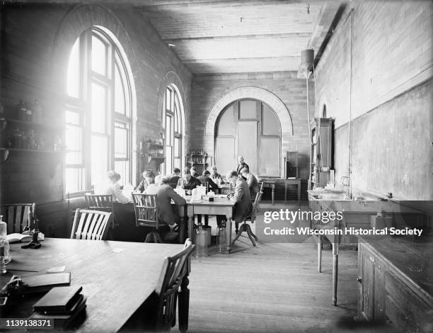 Interior view of a histological laboratory at the University of Wisconsin-Madison, Madison, Wisconsin, 1900. A group of students, men and women, are...