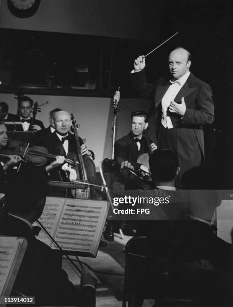 Russian conductor Andre Kostelanetz conducting an orchestra in a rendition of 'America The Beautiful', circa 1950.