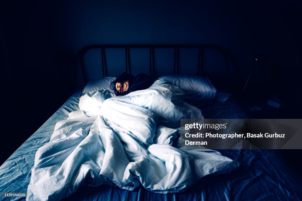 A woman sleeping in bed at night time