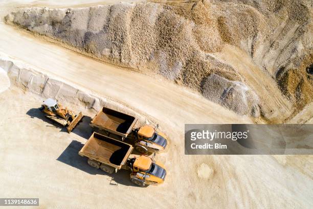 dump trucks and bulldozer in a quarry, aerial view - mining natural resources stock pictures, royalty-free photos & images
