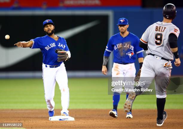 Richard Urena of the Toronto Blue Jays turns at double play against Brandon Belt San Francisco Giants at second base and Evan Longoria at first in...