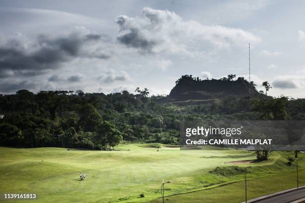 Two people walk on the green of the Sofitel Hotel to play golf, in Sipopo, nearly 16km from Malabo in Equatorial Guinea, on April 20, 2019. - In...