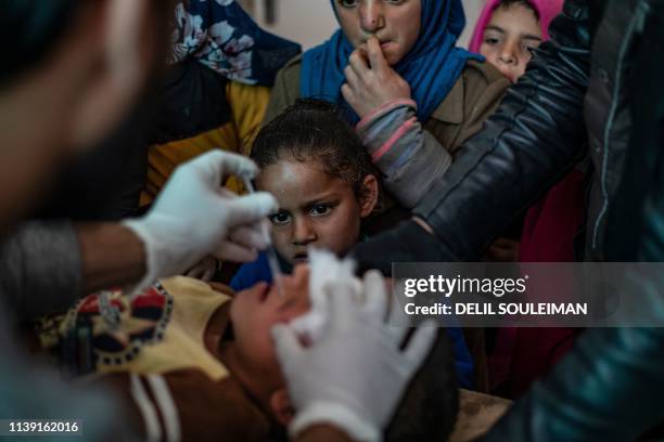 Syrian children look at a doctor injecting a child with a treatment for leishmaniasis skin disease at a health centre in Karama, in northern Syria,...