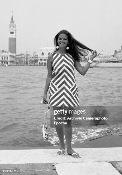 Italian actress Claudia Cardinale posing on the island of Giudecca, in front of St. Mark Square, wearing an optical dress and white round dangling...