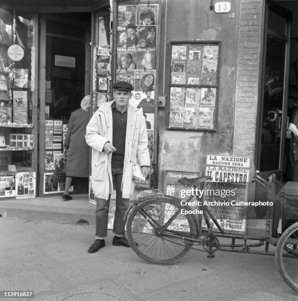 American jazz trumpeter Chesney Henry 'Chet' Baker standing in one Lucca's street, in front of a newsagent and next to a tricycle, wearing jeans, a...