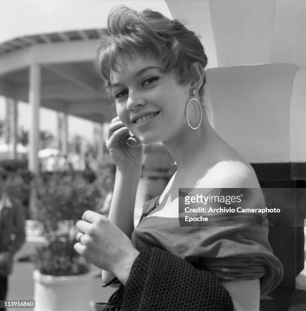 Young Brigitte Bardot, french model, singer and actress, at Cannnes Movie Festival, wearing a nude-back shirt and big round earrings, Cannes, 1955.