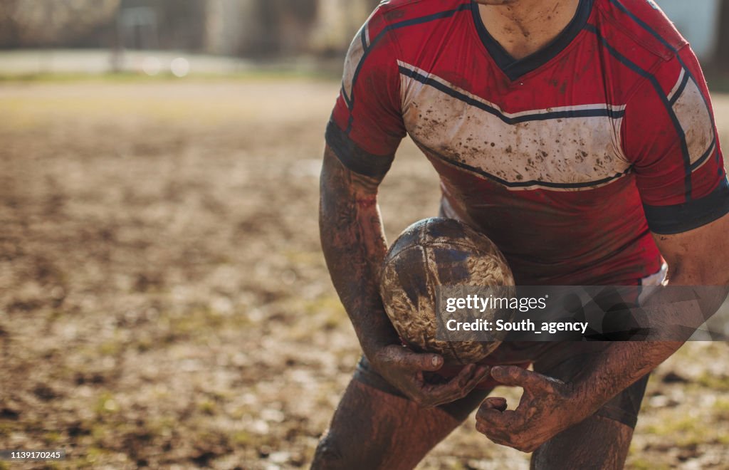 Rugby player standing on a playing field with ball