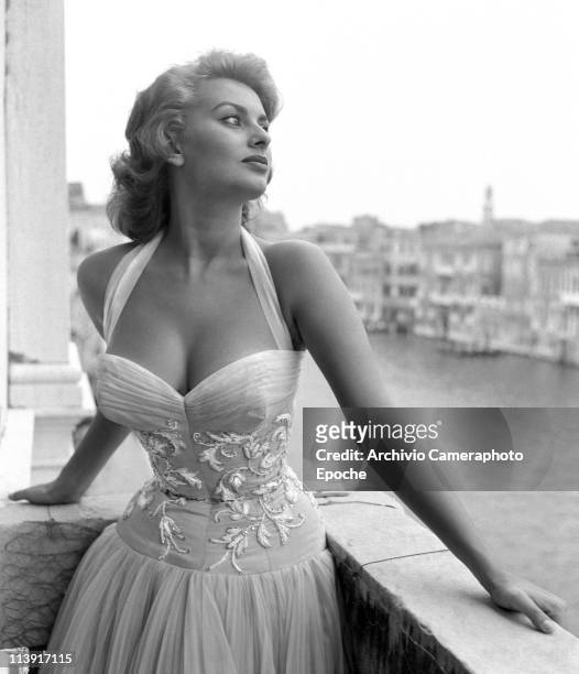 Italian actress Sophia Loren portayed standing on a terrace on the Canal Grande, wearing a white embroidered dress, Venice, 1955.