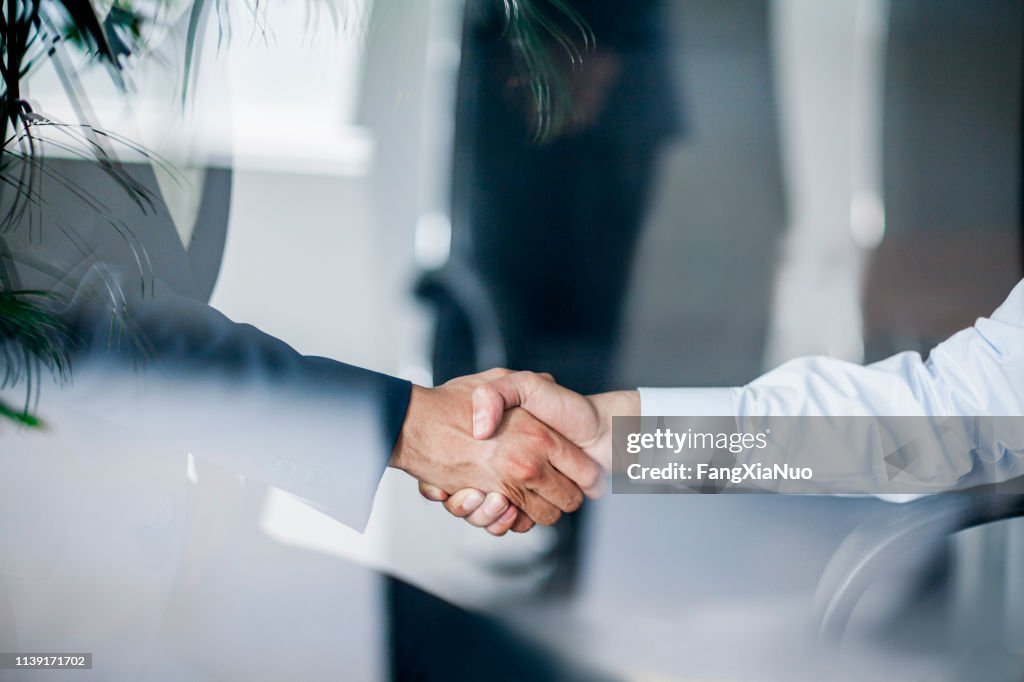 Business-Handschlag in Glasreflexion im Büro