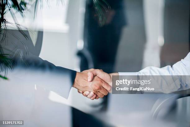 aperto de mão do negócio na reflexão de vidro no escritório - handshake - fotografias e filmes do acervo