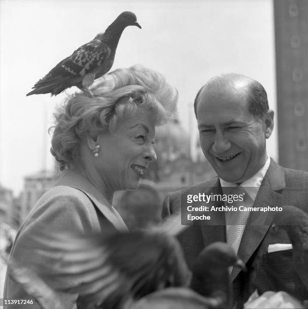 American art promoter David E. Bright and wife, a pigeon standing on her head, in St. Mark Square, in Venice for the Art Biennale 1958.