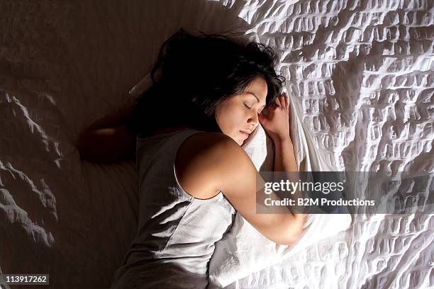 woman sleeping on bed - acostado de lado fotografías e imágenes de stock