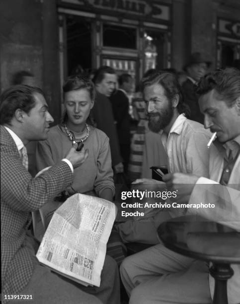 Scottish painter Alan Davie with wife, sitting outside Florian cafe in St. Mark Square, having a talk with two other men, Venice 1948.
