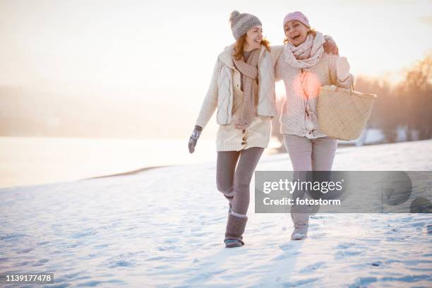 freunde lachen und im schnee spazieren - women winter snow stock-fotos und bilder