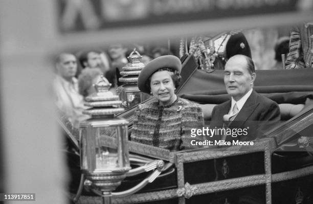 Queen Elizabeth II and Francois Mitterrand in a carriage during a state visit by the French President, London, 23rd October 1984.
