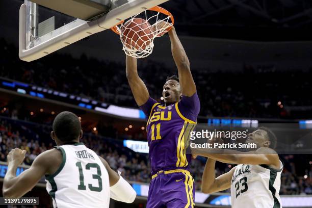 Kavell Bigby-Williams of the LSU Tigers dunks the ball against Gabe Brown and Xavier Tillman of the Michigan State Spartans during the second half in...