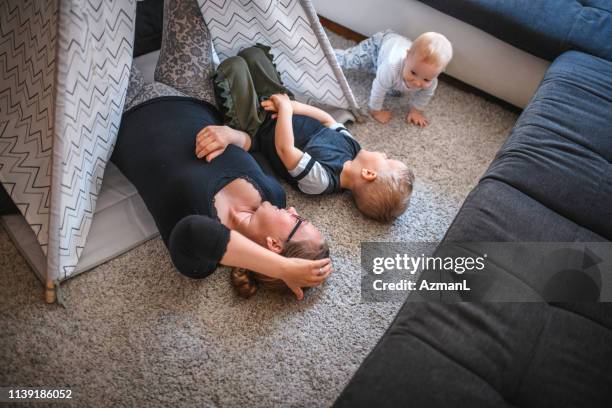 moeder en haar twee zonen hebben plezier in de woonkamer - kampeertent stockfoto's en -beelden