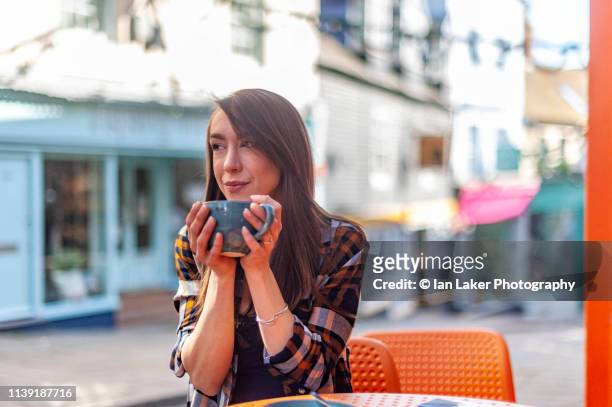 folkestone, kent, england. 24 march 2019. young woman drinking coffee outside coffee shop. - folkestone stock pictures, royalty-free photos & images
