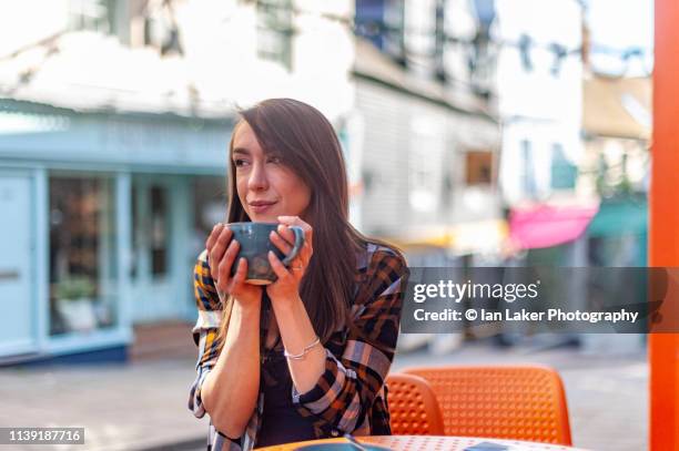 folkestone, kent, england. 24 march 2019. young woman drinking coffee outside coffee shop. - folkestone imagens e fotografias de stock