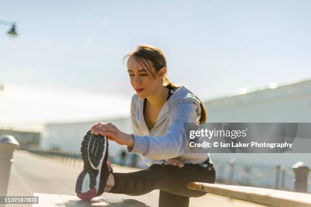 folkestone, kent, england. 24 march 2019. young woman stretching calf muscle. - female muscle calves stock pictures, royalty-free photos & images