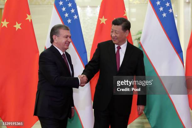 Uzbek president Shavkat Mirziyoyev, left, shakes hands with Chinese President Xi Jinping, right, before the meeting at the Great Hall of People on...