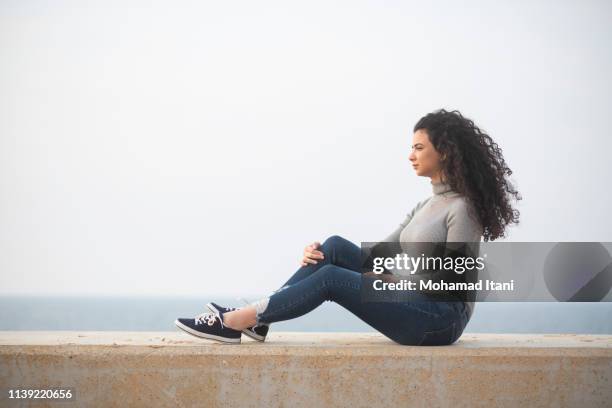 young woman sitting on the beach - beiroet beach stockfoto's en -beelden