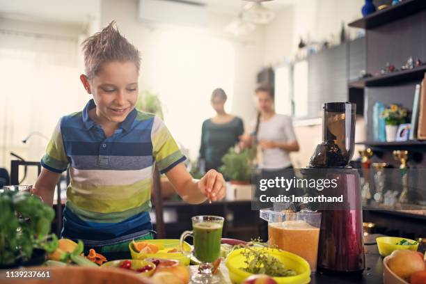 kleine jongen versieren veganistisch sap van groenten en fruit - vegetarisme stockfoto's en -beelden