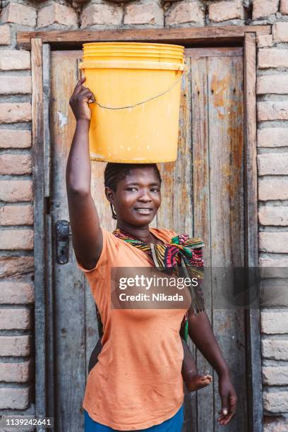 african mother with baby son and water bin at home - 1 year poor african boy stock pictures, royalty-free photos & images