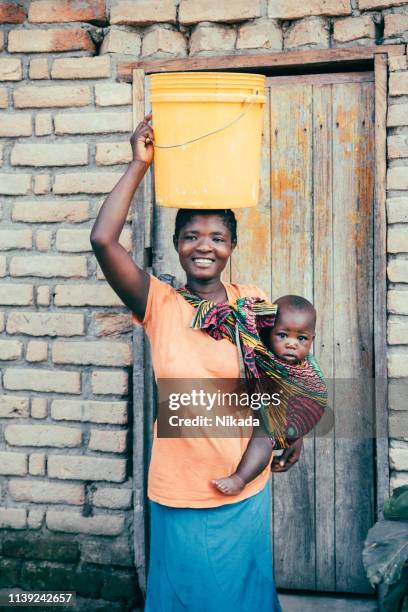 african mother with baby son and water bin at home - 1 year poor african boy stock pictures, royalty-free photos & images