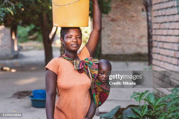 african mother with baby son and water bin at home - 1 year poor african boy stock pictures, royalty-free photos & images