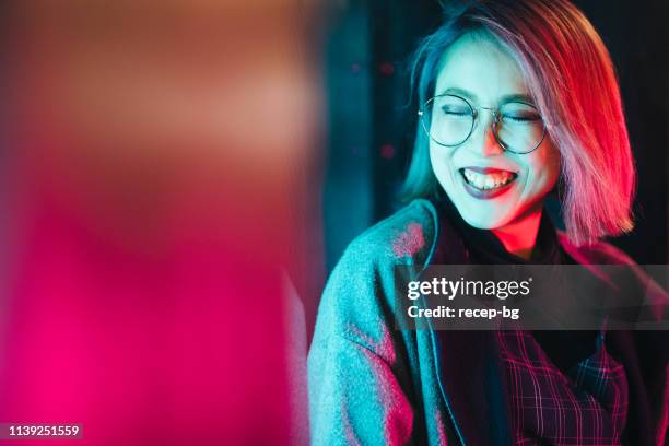 porträt der jungen und glücklichen frau, die von neonlicht beleuchtet wird - hipster brille stock-fotos und bilder