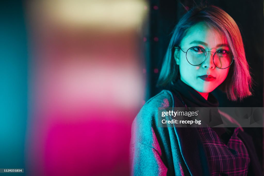 Portrait of young woman lit up by neon lights