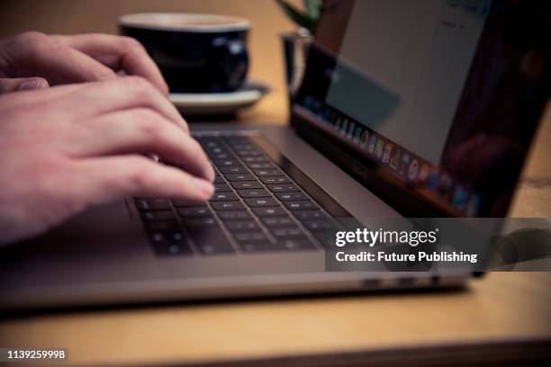 Detail of someone typing on the keyboard of an Apple MacBook Pro laptop computer in a cafe, taken on November 18, 2016.